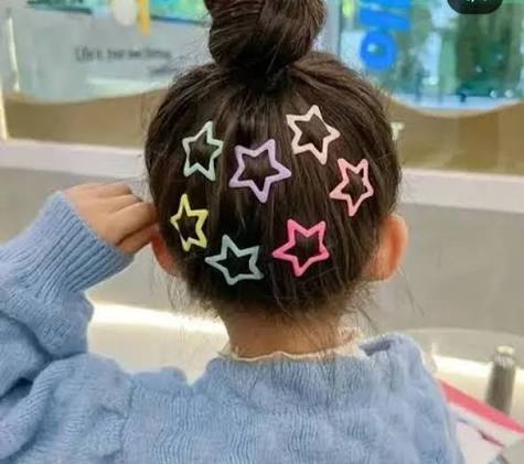 Girl wearing colorful star shape hair clips in bun hairstyle